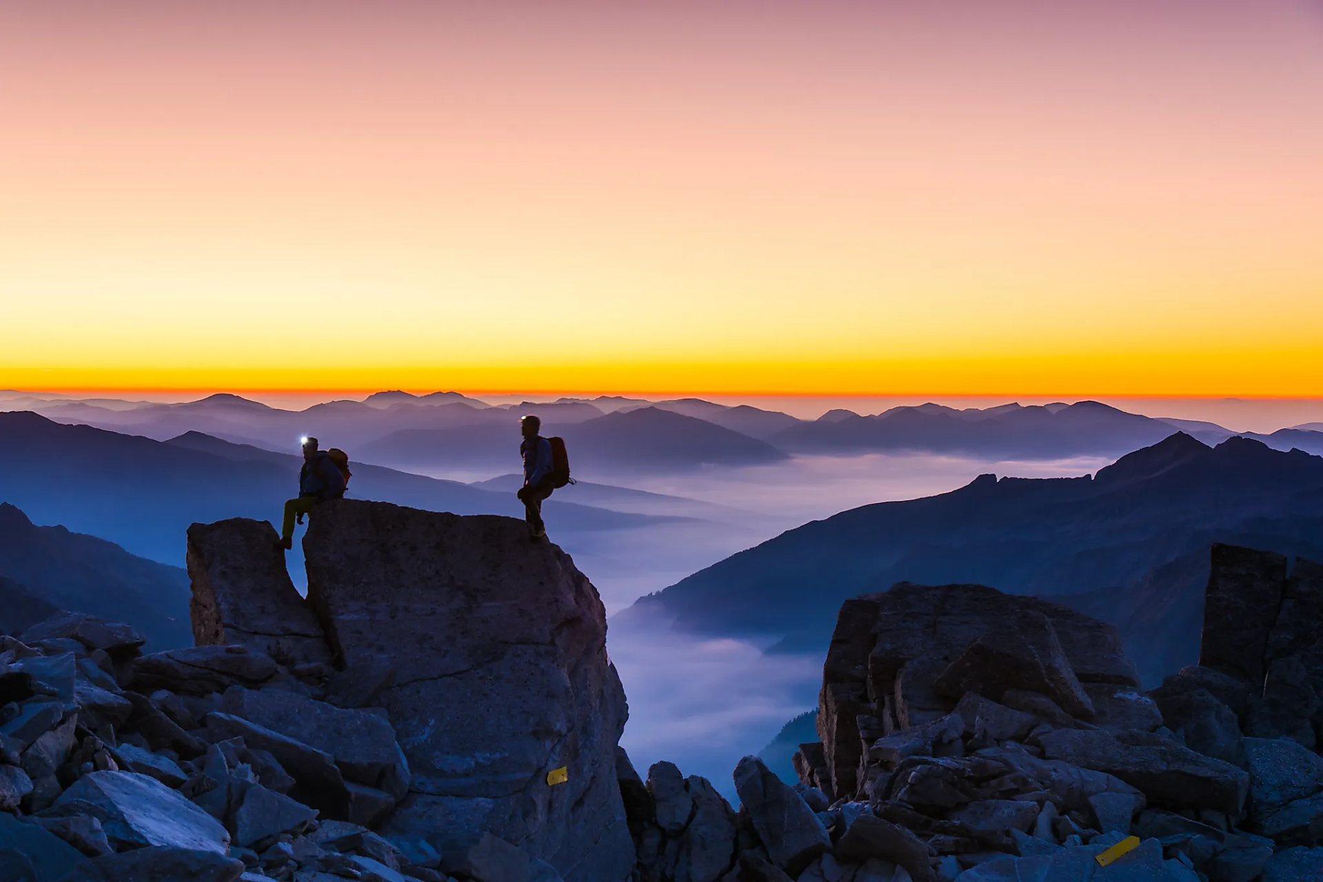 Bergsteiger auf Felsen beim Sonnenaufgang